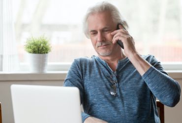Man on phone in front of laptop