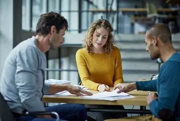 Three people deliberating around a table
